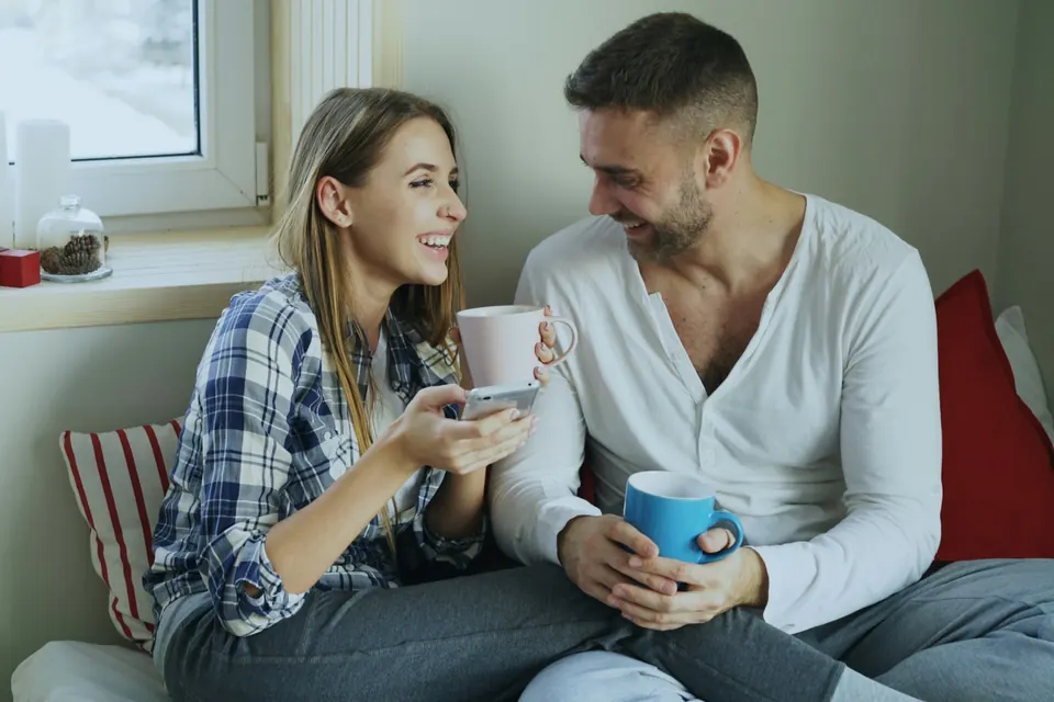 A couple smiling and talking over coffee by the window