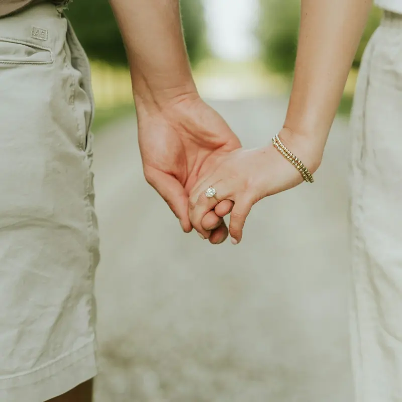 A couple holding hands as they walk along a path